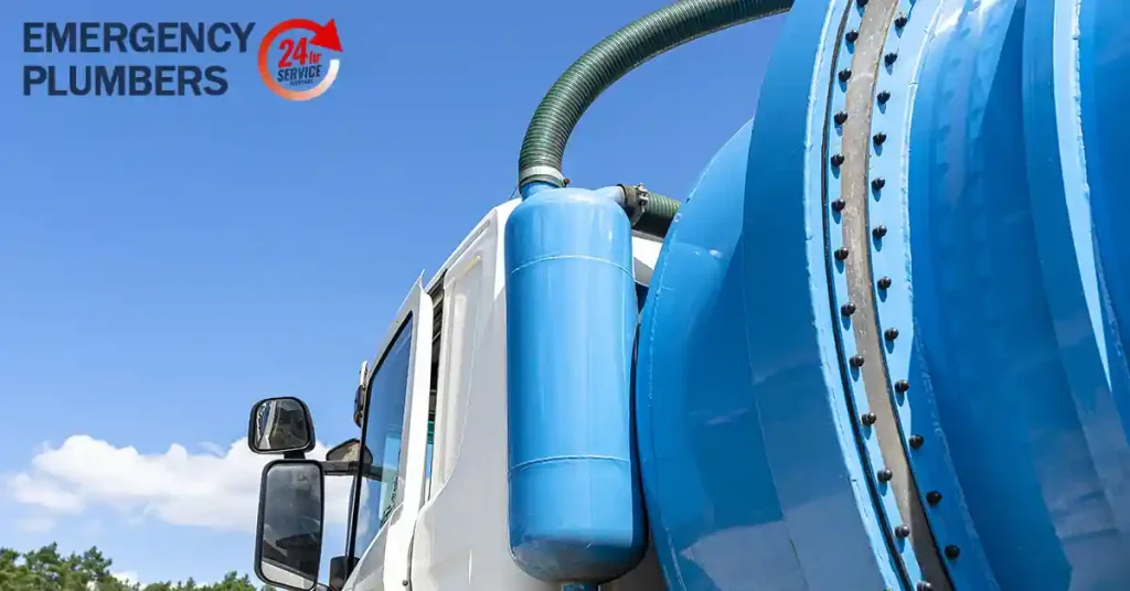Close-up of a blue and white emergency plumbing truck with a "24/7 Service" logo and "Emergency Plumbers" text in the top left corner.